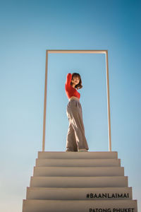 Low angle view of woman standing against clear sky