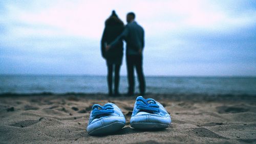 Low section of man on beach against sky