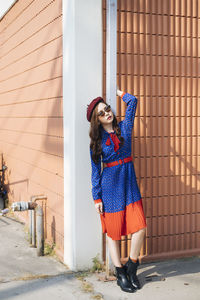 Full length of woman standing against wall