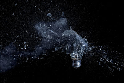 Close-up of broken light bulb against black background