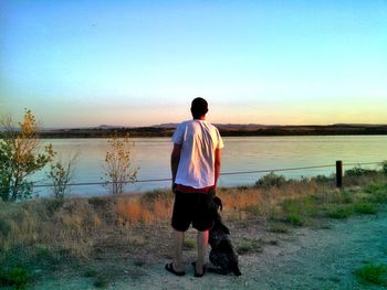 Rear view of man standing at beach against clear sky