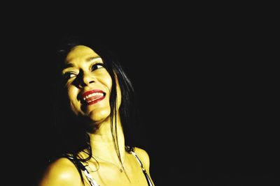 Portrait of young woman looking away over black background