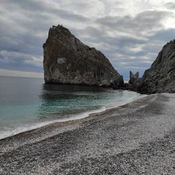 Rock formation on beach against sky