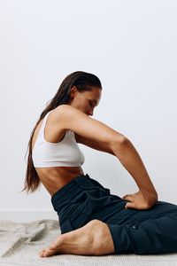 Side view of young woman sitting against white background