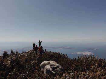 Hikers on cliff against sky