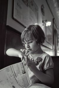 Girl reading newspaper at home