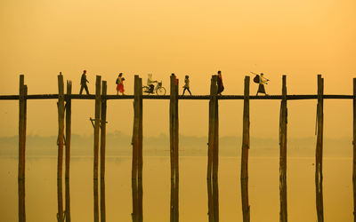 People crossing u bein bridge at sunset