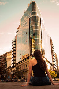 Rear view of woman standing against modern building