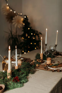 Cozy xmas interior in natural rustic style with table decorated with burning candles and decorative elements in room with glowing garland