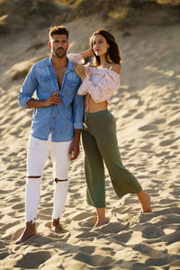 Full length of young couple standing at beach