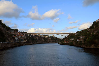 Bridge over river against cloudy sky