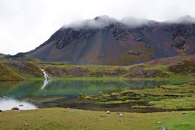 Scenic view of lake by mountains against sky