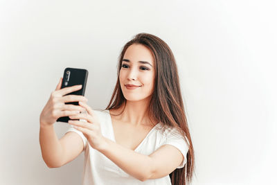 Young woman using smart phone against white background