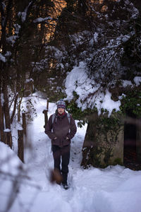 Man standing on snow covered tree