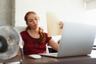 Young woman using mobile phone while sitting on table