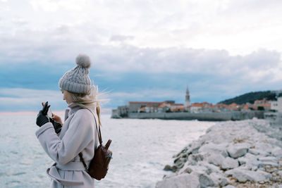 Rear view of woman standing against sea