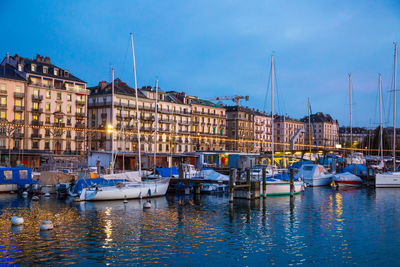 Sailboats moored in sea against sky in city