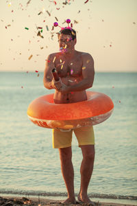 Full length of shirtless man standing on beach