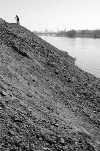 Person on rock by land against sky