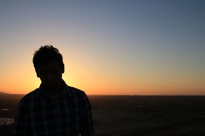 Young man standing against landscape during sunset