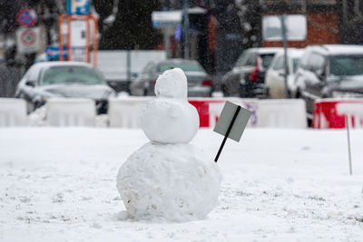 Snowman in the yard of a residential house, isolated on a defocused city background