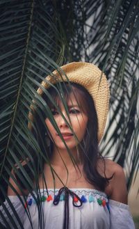 Portrait of young woman wearing hat standing against plants