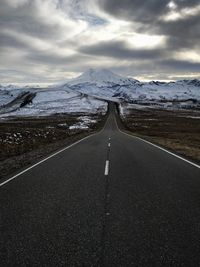 Road leading towards mountain against sky