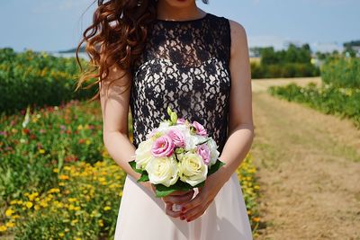 Midsection of woman holding umbrella standing on field