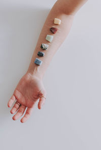 Cropped hand of woman with crystals against white background