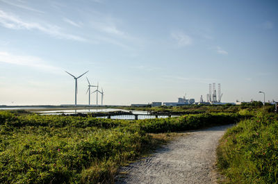 Wind turbines on field against sky