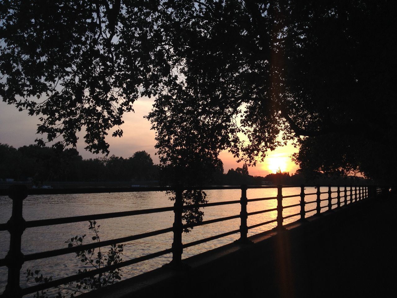 SILHOUETTE RAILING BY RIVER AGAINST SKY AT SUNSET