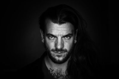 Close-up portrait of young man against black background