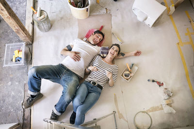 Happy couple renovating new home, taking a break, daydreaming