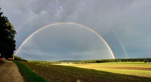 Scenic view of rainbow over field against sky