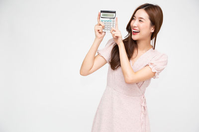 Smiling young woman using smart phone against white background