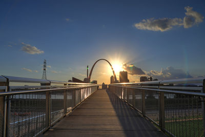 Footbridge against sky during sunset