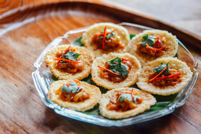 Crispy rice cake and pork and shrimp dipping in plate on wood table. thai food