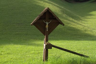 Jesus figurine on wooden pole at grassy field