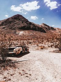 Damaged car on mountain road against sky