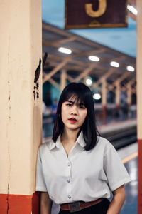 Portrait of young woman standing against wall