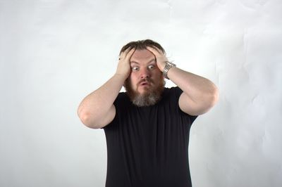 Frustrated man standing against white background