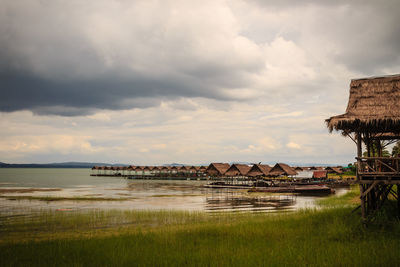 Houses on field by sea against sky