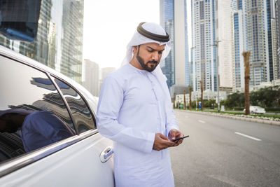 Man using mobile phone while standing on city street