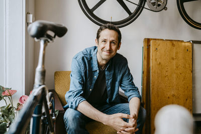 Portrait of young man sitting on chair at home