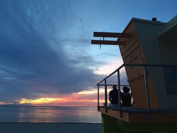 Silhouette of people on sea at sunset