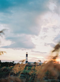 Lighthouse on beach against sky during sunset