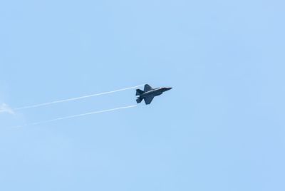 Low angle view of military airplane against clear sky on sunny day