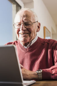 Senior man sitting at home, using laptop