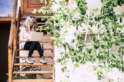 Woman sitting on seat in front of plants