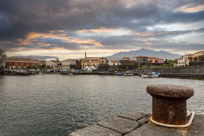 View of a small sicilian fishing port. in the background stands the etna volcano